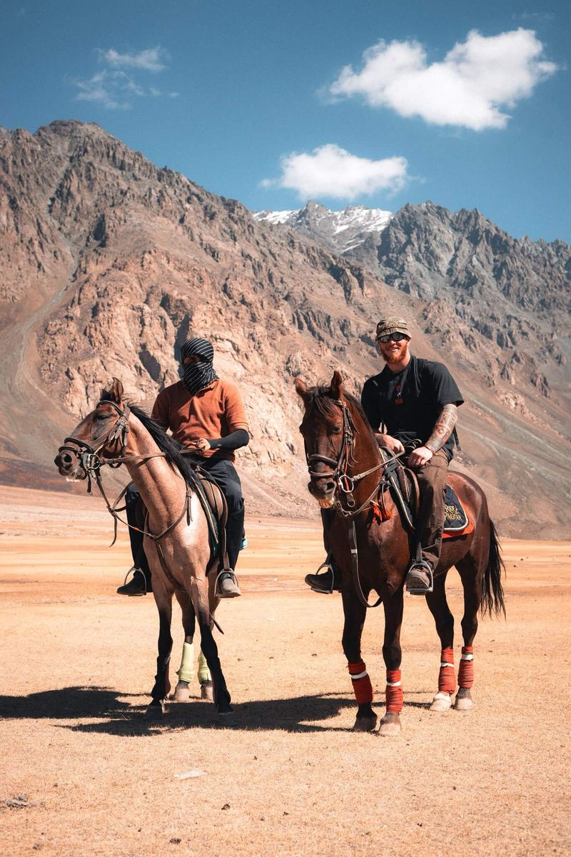 Two Frontiersmen riders below high arid mountains under a blue sky